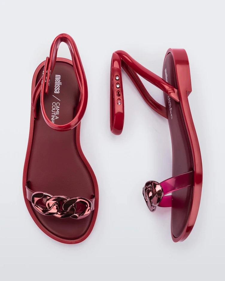 A top and side view of a pair of red Melissa Dare sandals with a red metal chain buckle.