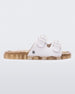 An outter side view of a Beige Mini Melissa Wide Slide with a white top with two white buckles and a beige sole.