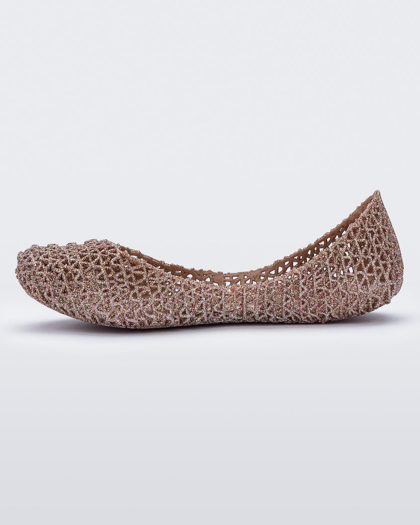 An inner side view of a pink metallic Mini Melissa Campana flat with a woven design base.
