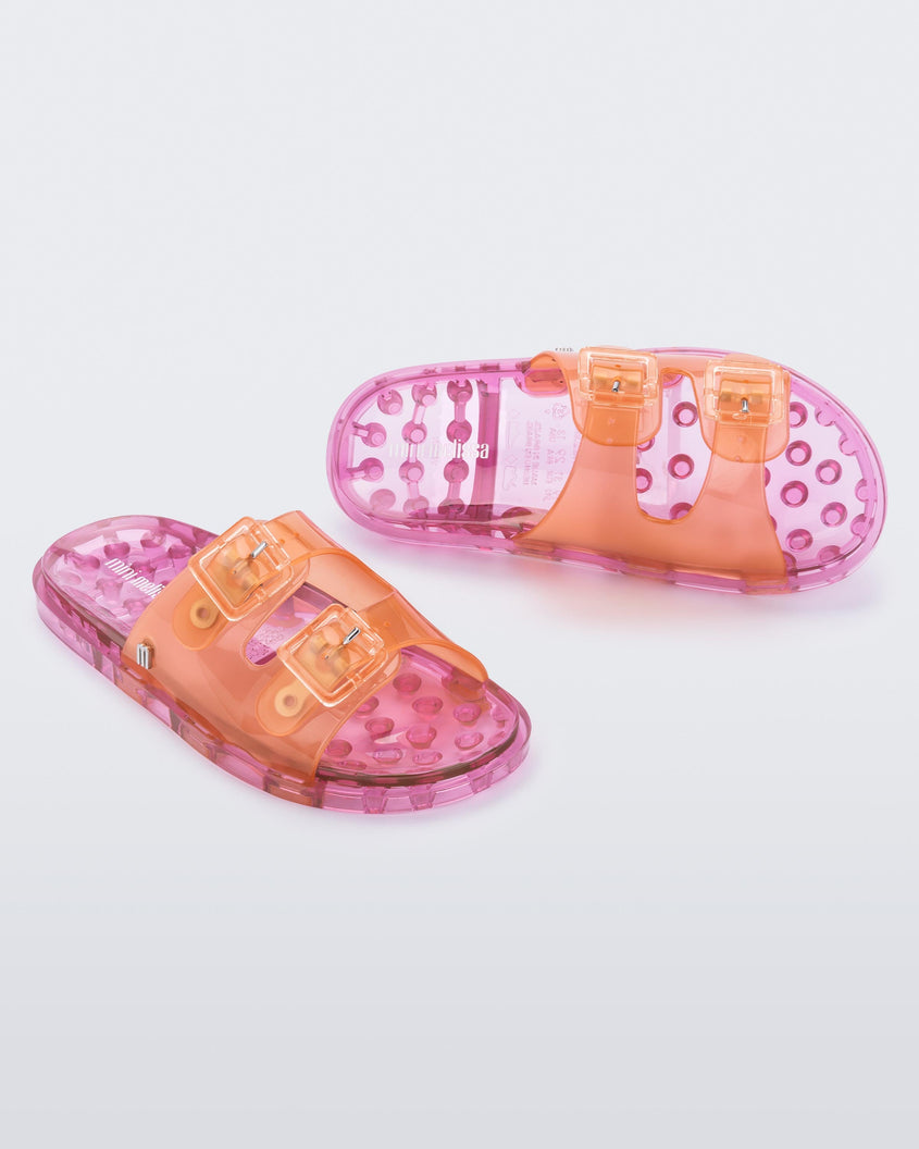 An angled front and top view of an orange/pink Mini Melissa Wide Slides with an an orange top with two silver buckles and a pink sole.