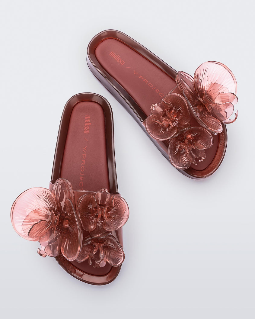 Top view of a pair of red Melissa Flower Beach slides with flowers on the top.
