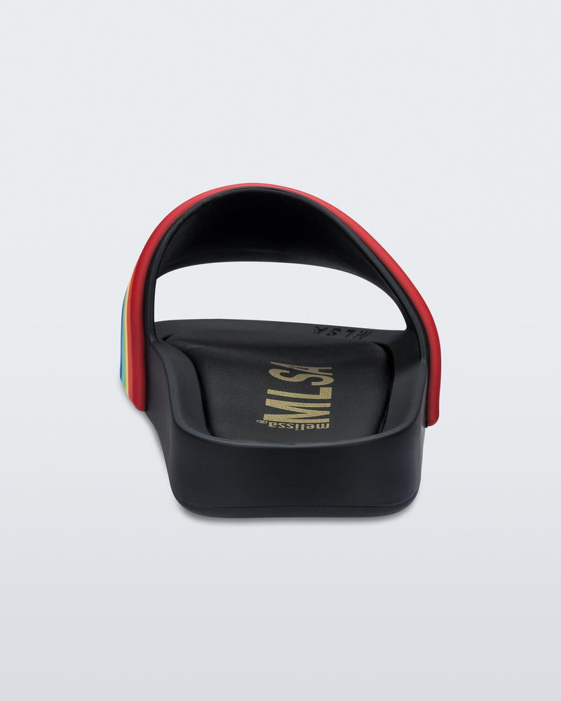 Back view of a black rainbow Melissa Rainbow Beach slide with a black base and a rainbow design on the front strap.