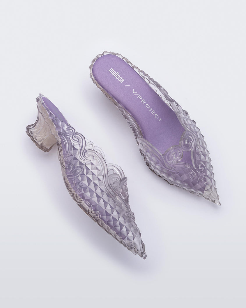 Top and side view of a pair of Melissa Court mules in clear with a kitten heel and diamond- like pattern. 