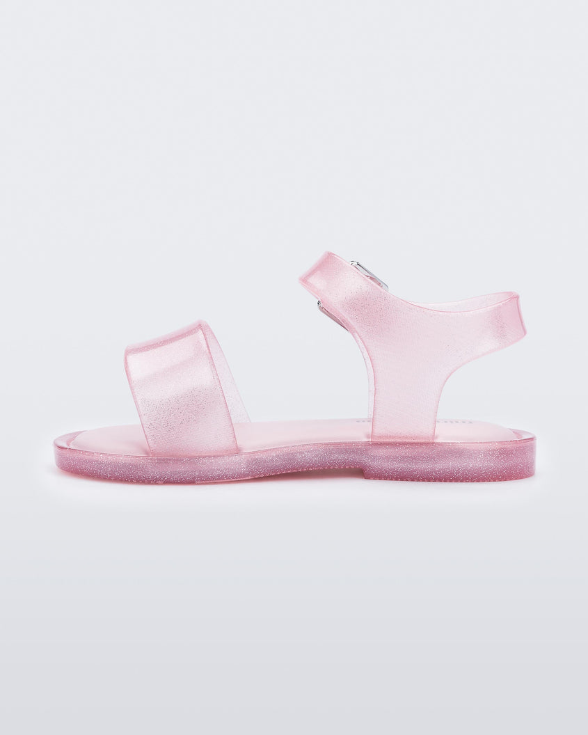 An inner side view of a pink glitter Mini Melissa Mar Sandal with two straps and a metal buckle.