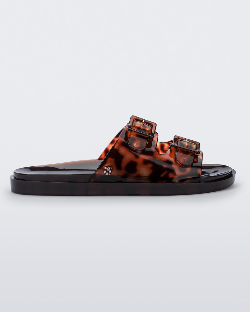 Side view of a Melissa Wide slide sandal with brown sole and  Brown Tortoise colored straps