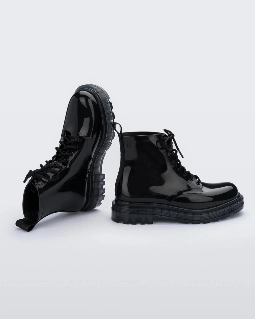An angled top and side view of a pair of black Melissa Coturno boots with a black base, laces and sole.