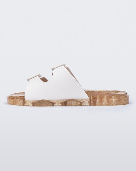 Inner side view of a Melissa Wide slide sandal with gold glitter sole and white double straps with buckles