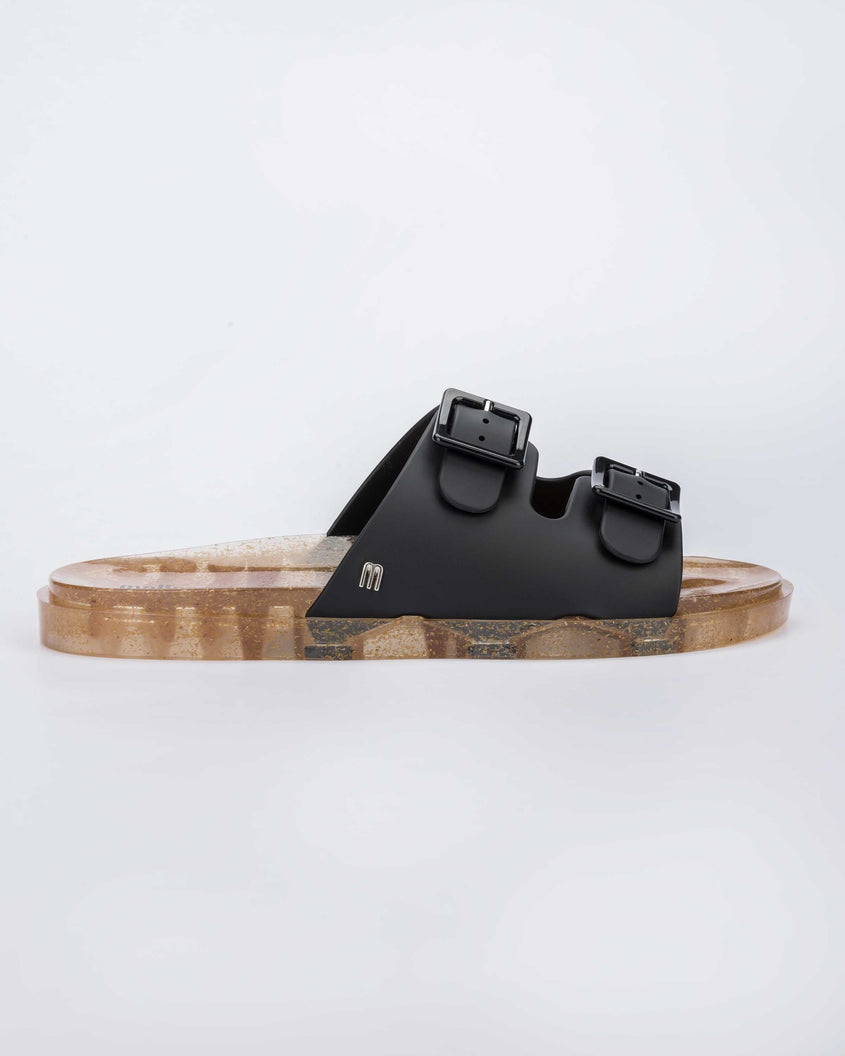 Side view of a Melissa Wide Slide sandal with gold speckled sole and two black front straps
