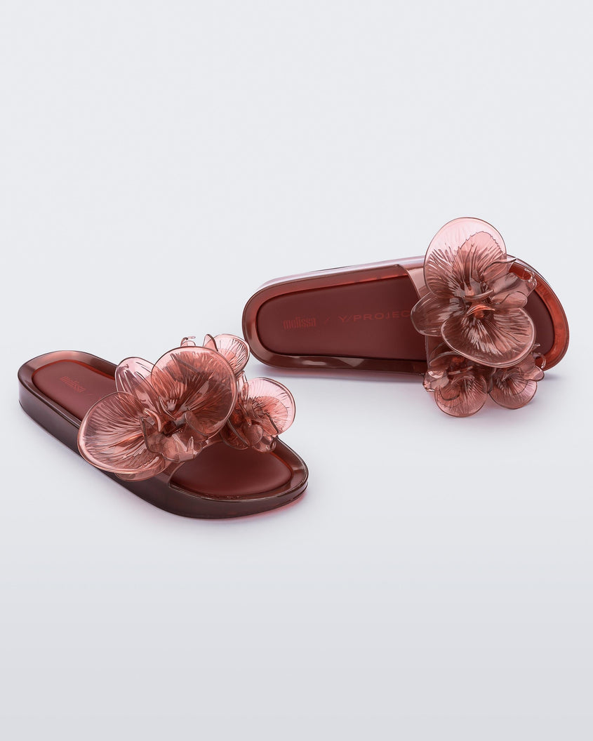 A top and side view of a pair of red Melissa Flower Beach slides with flowers on the top.