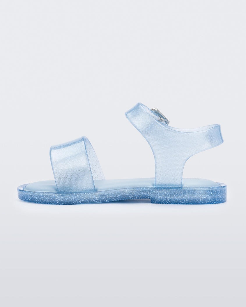 An inner side view of a blue glitter Mini Melissa Mar Sandal with two straps and a metal buckle.