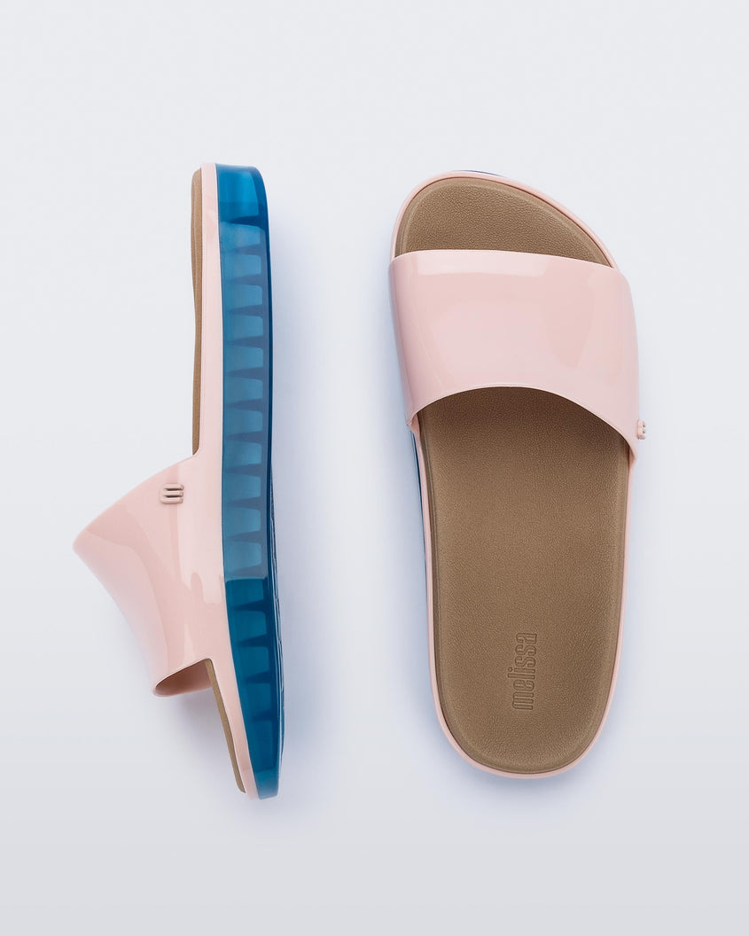 Top and side view of a pair of pink Melissa Beach slides with blue soles. 
