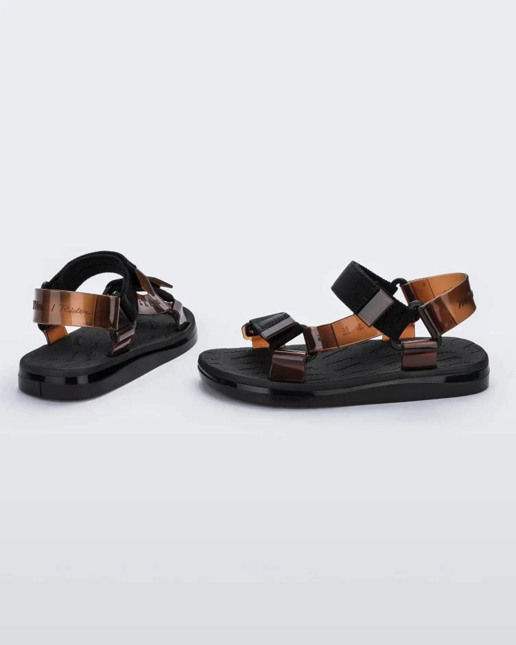 Side and back view of a pair of black Melissa Papete sandals with black and transparent brown straps.
