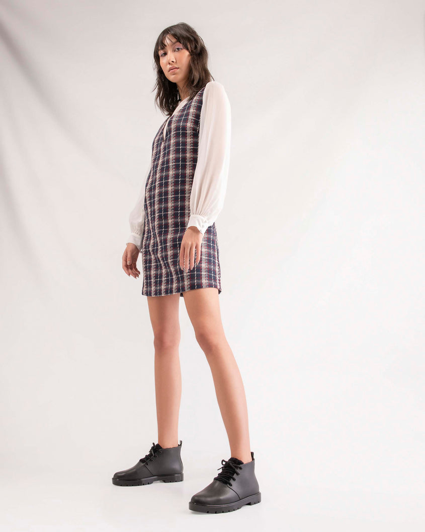A model posing for a picture in a plaid dress and wearing a pair of black Melissa Fluffy Boots with laces and a rubber sole.