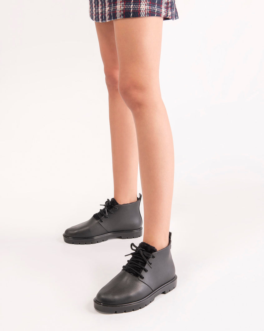 A model's legs wearing a pair of black Melissa Fluffy Boots with laces and a rubber sole.