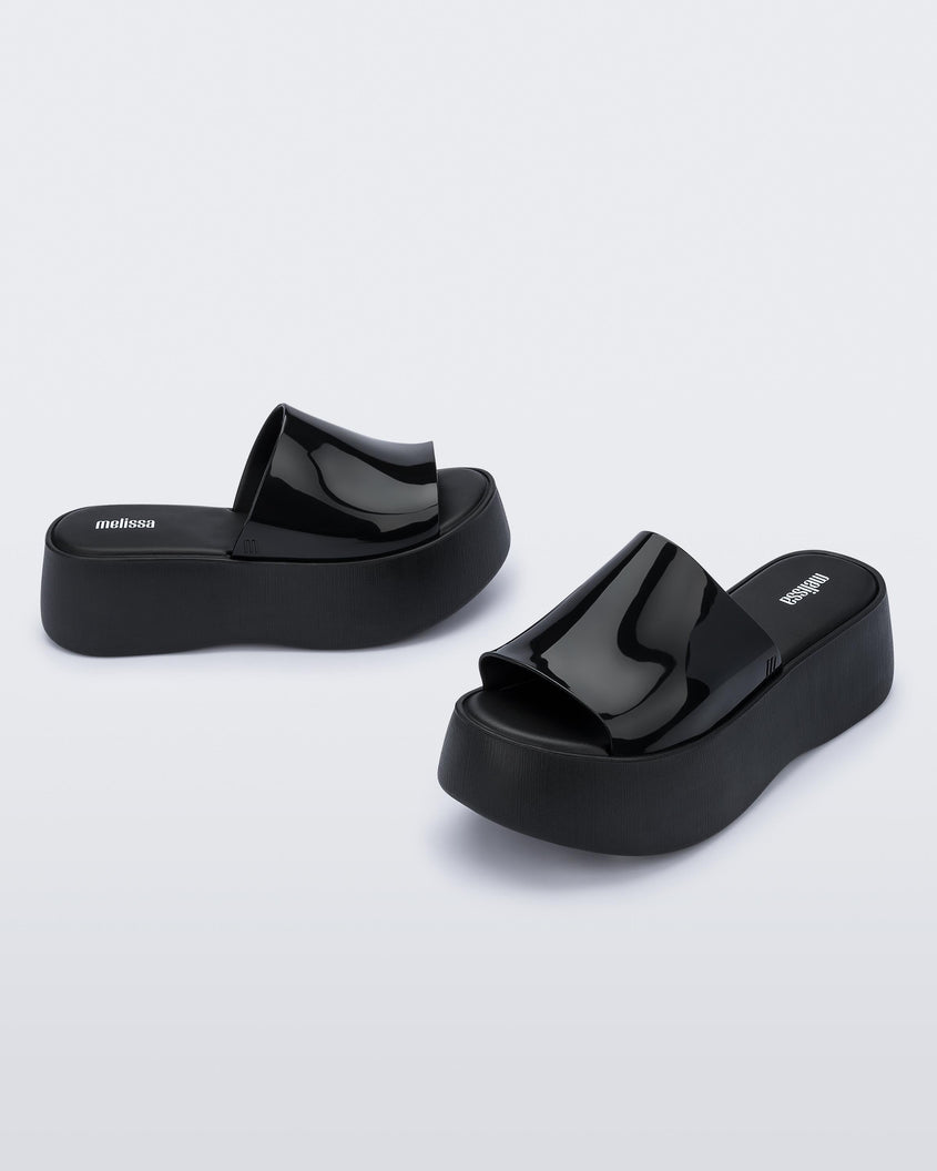 Angled view of a pair of black Melissa Becky platform slides. 