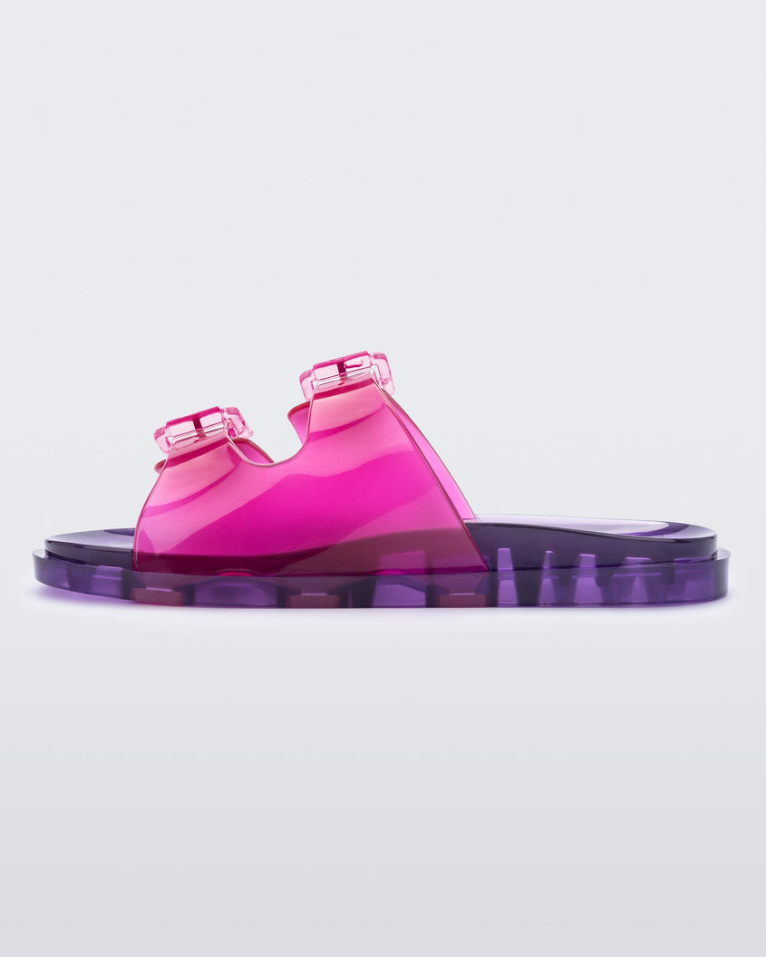 An inner side view of a pink/lilac Mini Melissa Wide Slide with a pink top with two pink buckles and a lilac sole.