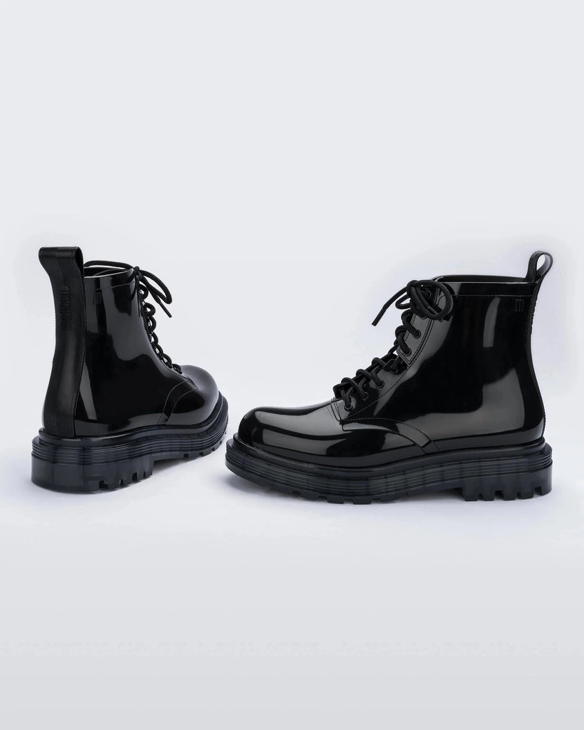 An angled back and side view of a pair of black Melissa Coturno boots with a black base, laces and sole.
