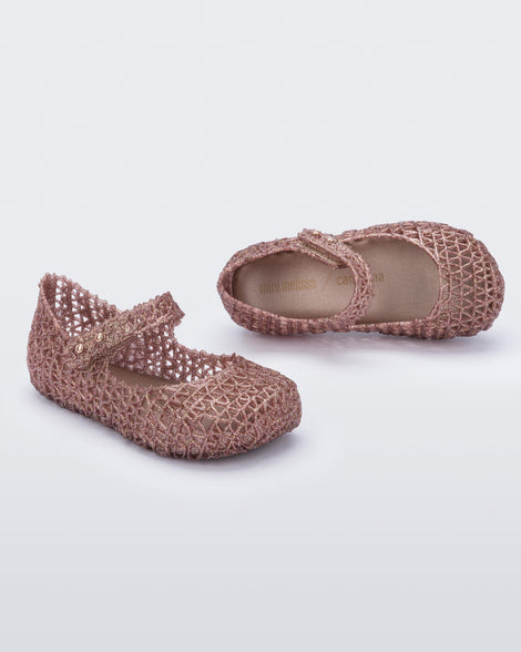 Top and angled view of a pair of Mini Melissa Campana flats for baby in rose glitter with an open woven texture.