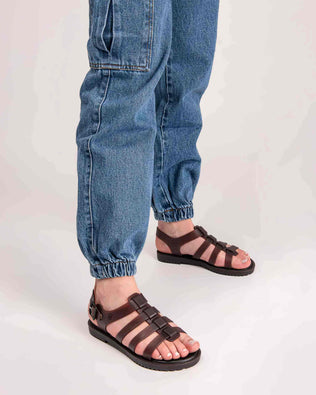 A model's legs wearing a pair of clear brown Melissa Flox sandals with straps.