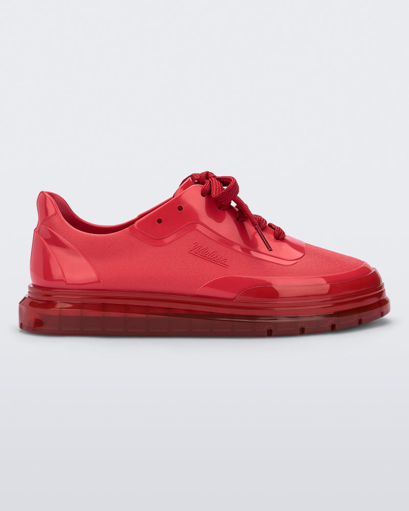 Side view of a red Melissa Classic sneaker with a red base, laces, sole and a melissa logo on the side