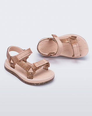Angled view of a pair of pink Mini Melissa Papete sandal with pink and glitter straps.