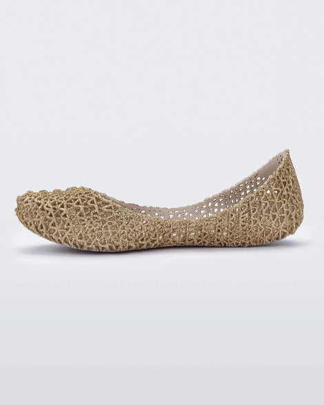 An inner side view of a pair of white / gold glitter Mini Melissa Campana flats with an open woven texture.