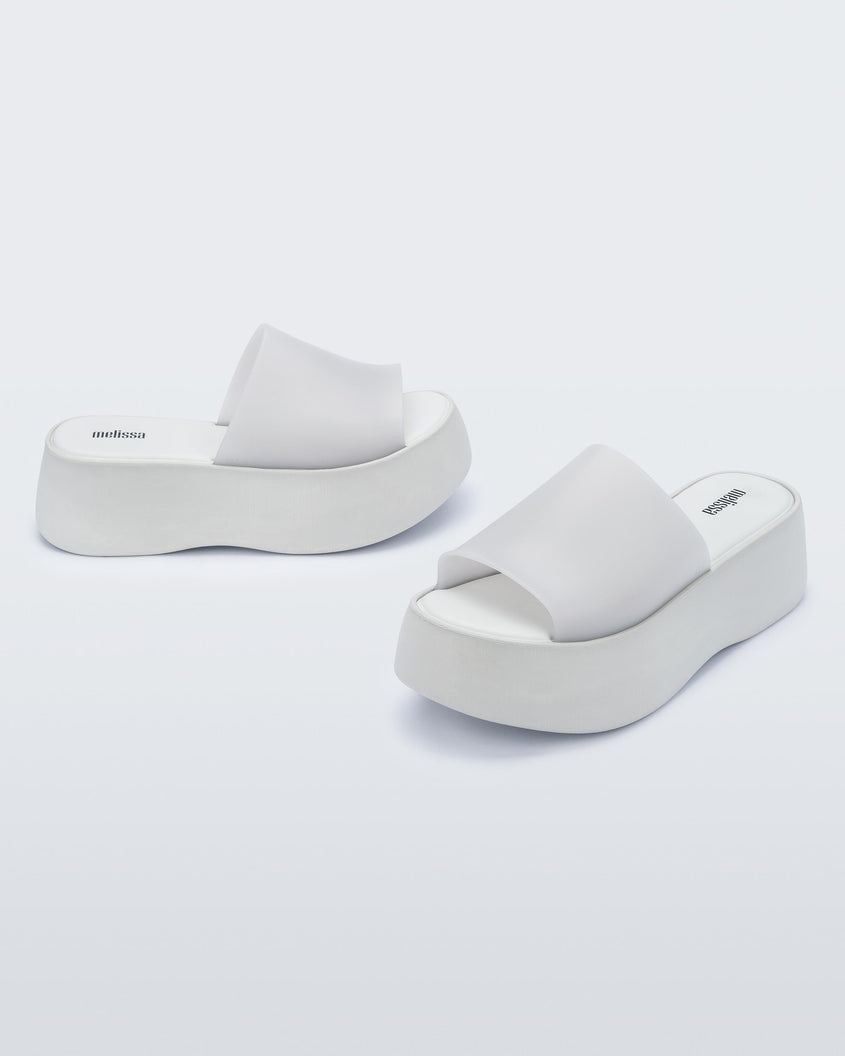 Angled view of a pair of white Melissa Becky platform slides. 