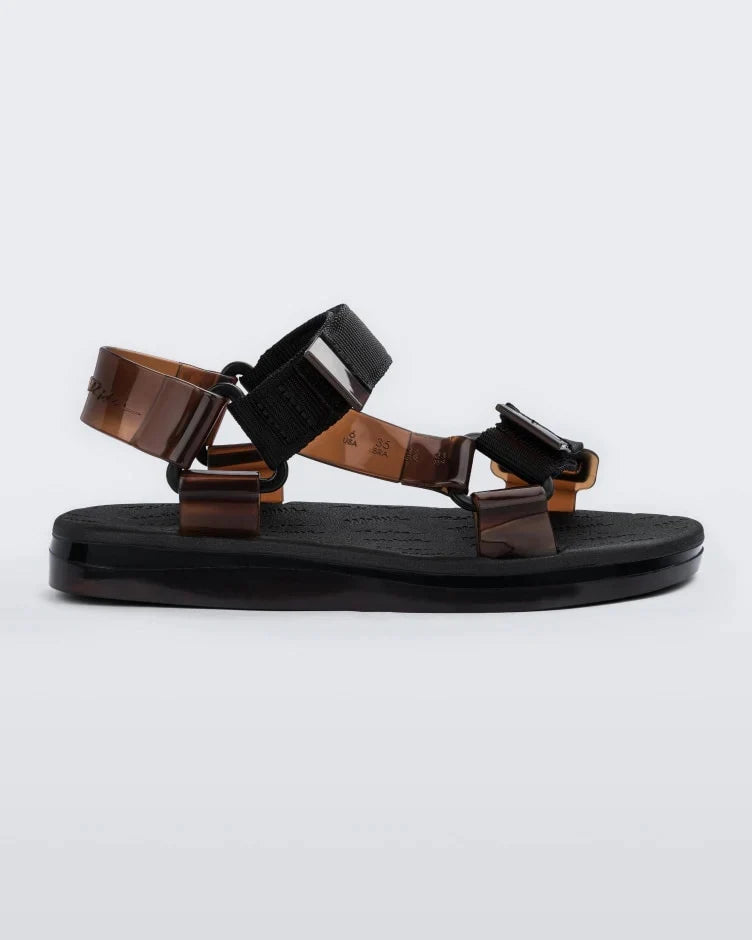 Side view of a pair of black Melissa Papete sandals with black and transparent brown straps.