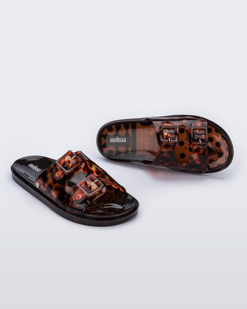 Top and angled view of a pair of Melissa Wide slide sandals with brown sole and  brown tortoise colored straps