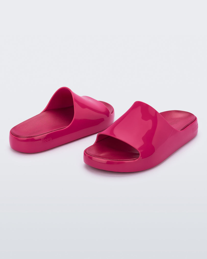 An angled front and back view of a pair of pink Melissa Cloud slides.