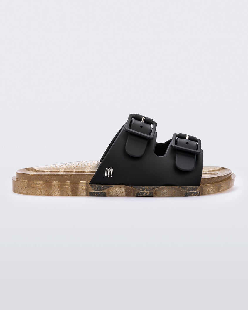 An outter side view of a Black/Beige Mini Melissa Wide Slide with a black top with two black buckles and a beige sole.