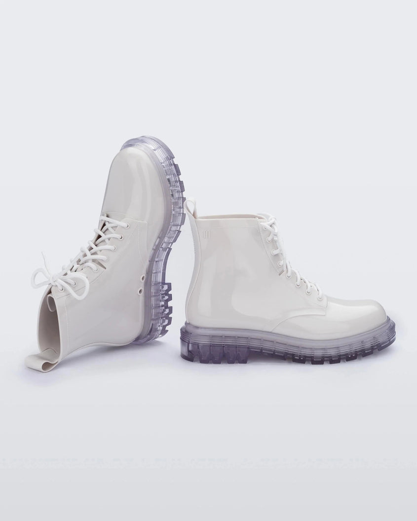An angled top and side view of a pair of white/clear Melissa Coturno boots with a white base, laces and a clear sole.