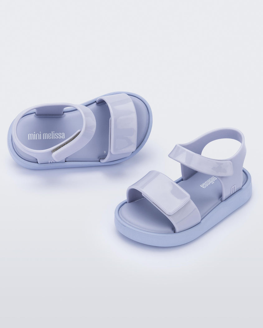 An angled top and side view of a pair of purple Mini Melissa Jump sandals with velcro straps.