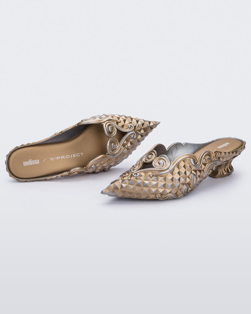 Top and angled view of a Melissa Court mule with gold and silver coloring, a kitten heel and diamond- like pattern. 