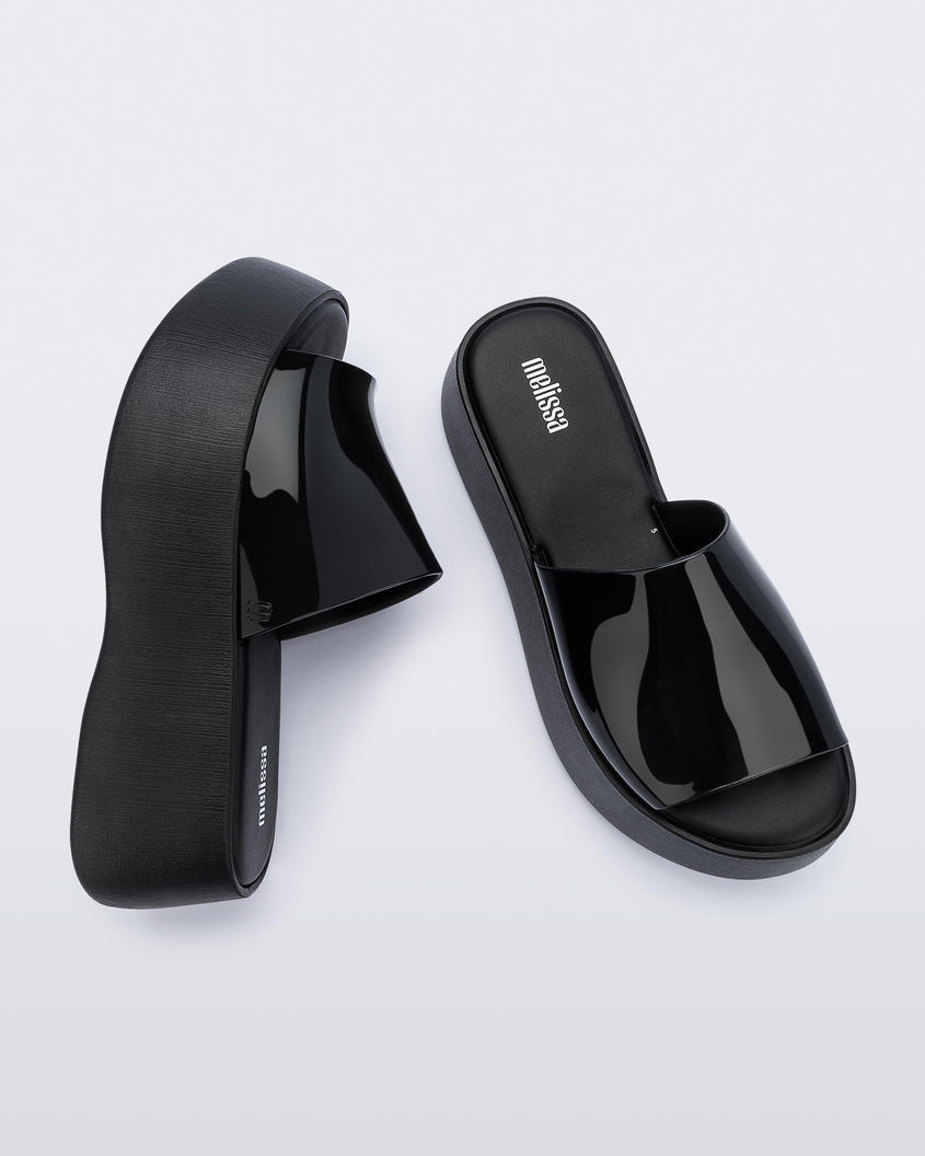 Top and side view of a pair of black Melissa Becky platform slides. 