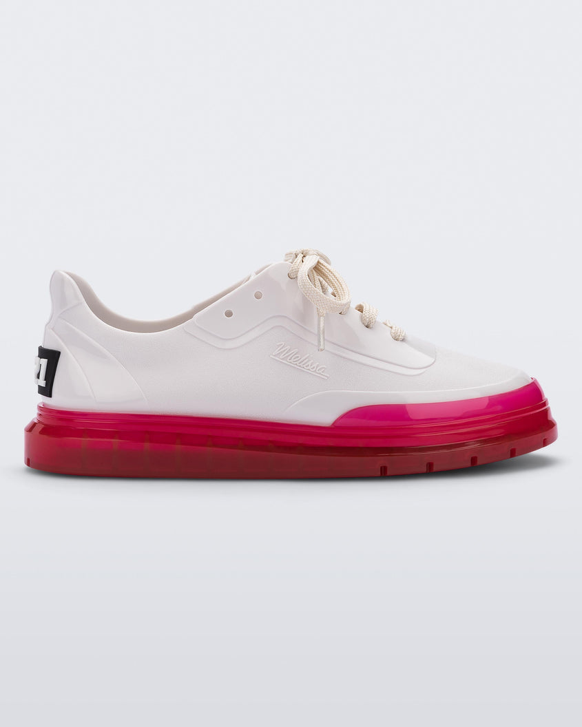 Side view of a white Melissa Classic sneaker with a white base, laces, pink sole and a melissa logo on the side.