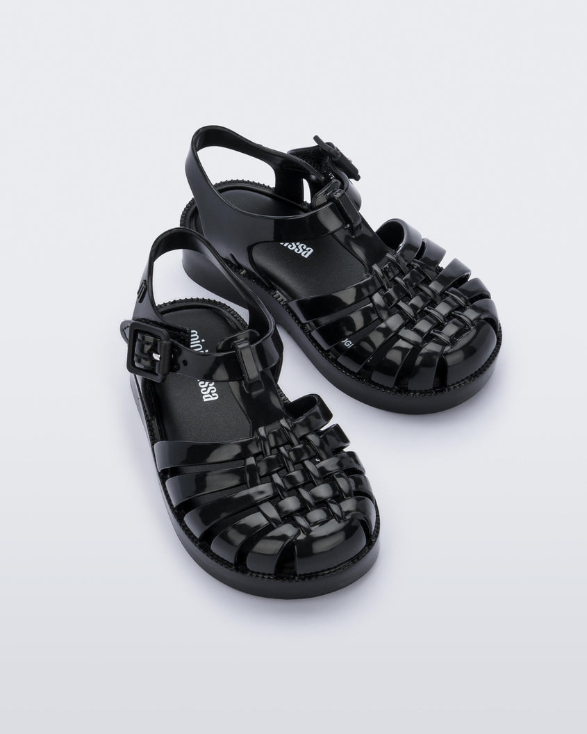 An angled front view of a pair of black Mini Melissa Possession sandals with several straps with a closed toe front.