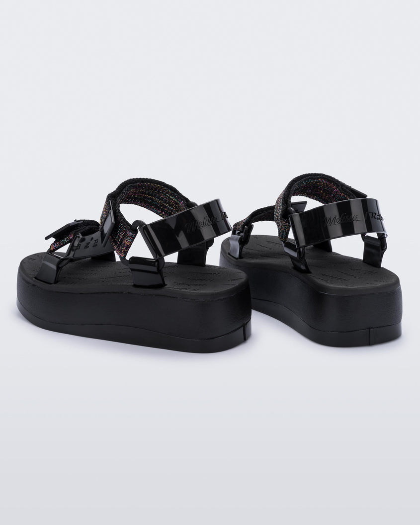 A back view of a pair of black Melissa Papete Platform sandals with a black multicolor straps.