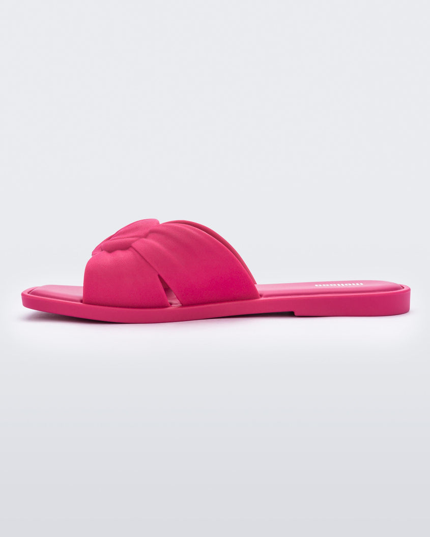 An inner side view of a pink Melissa Plush slides with a twist front strap detail.