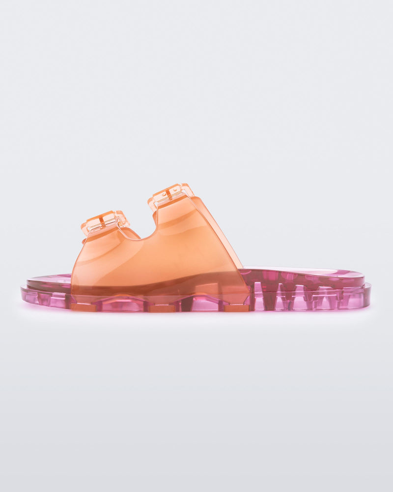 An outter side view of an orange/pink Mini Melissa Wide Slide with an an orange top with two silver buckles and a pink sole.