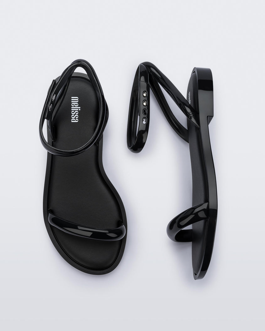 A top and side view of a pair of black Melissa Wave Sandal with one front strap and one ankle strap.