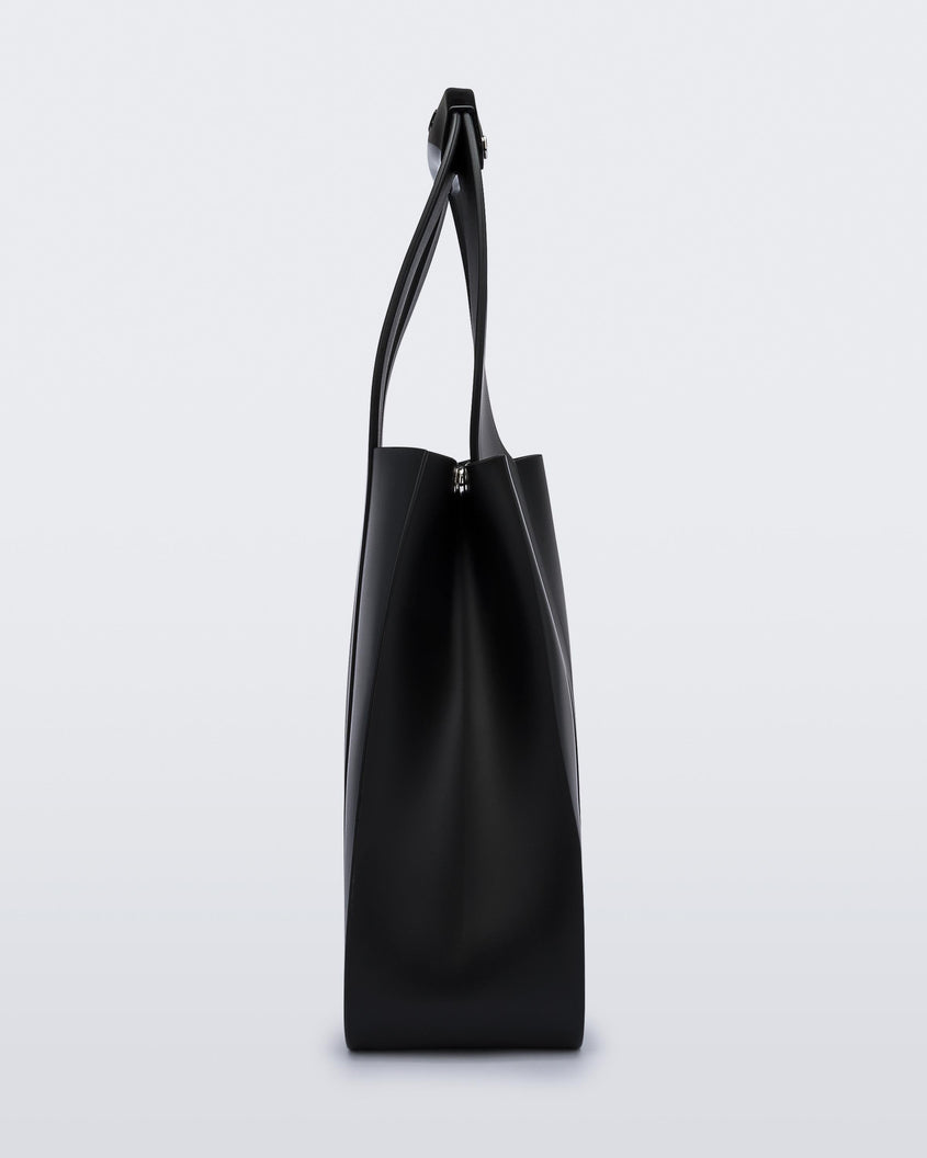 Side view of a black Melissa Essential Tropicana bag with a circular handle.