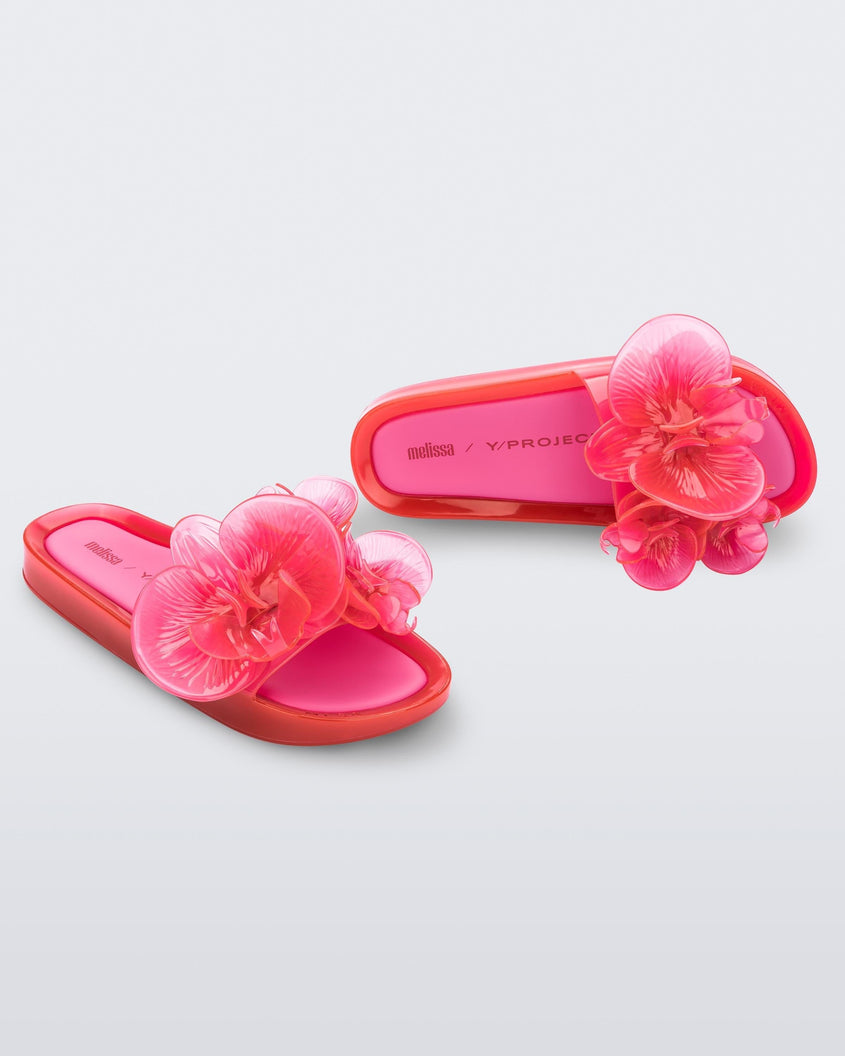 A top and side view of a pair of pink Melissa Flower Beach slides with flowers on the top.