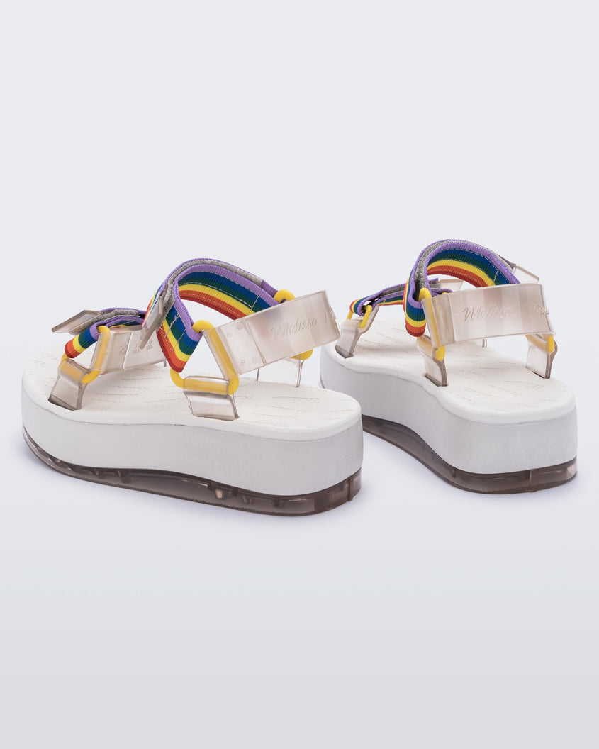 A back view of a pair of white Melissa Papete Platform sandals with clear and rainbow straps.