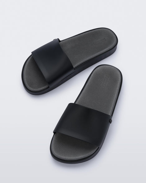 Angled view of a pair of black Melissa Beach slides. 