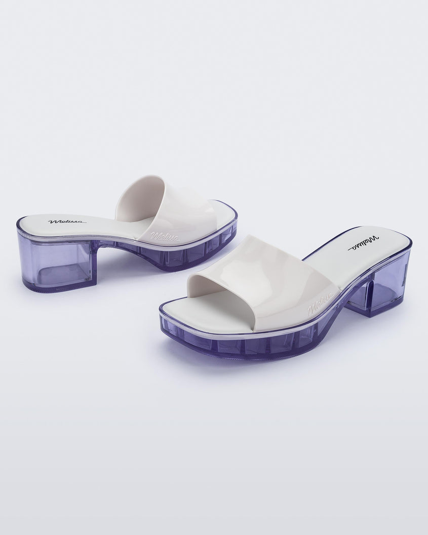 Angled view of a pair of Melissa Shape slides with clear heel and white wide strap 