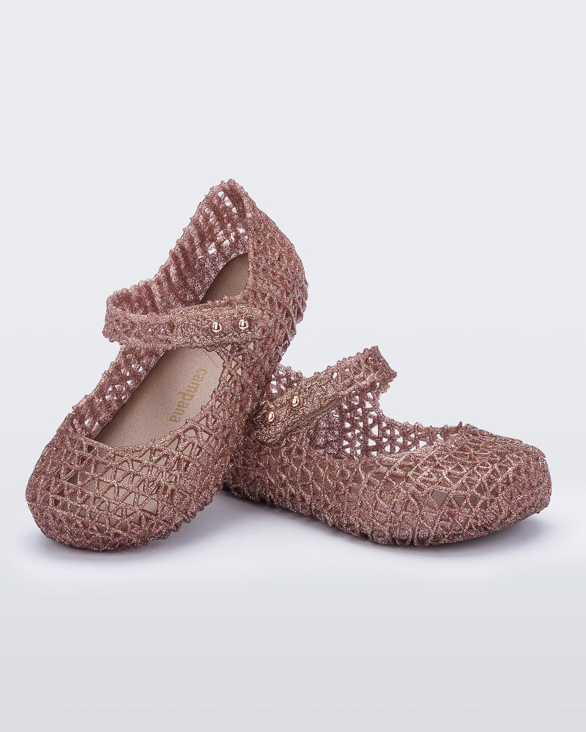 Angled view of a pair of Mini Melissa Campana flats for baby in rose glitter with an open woven texture.