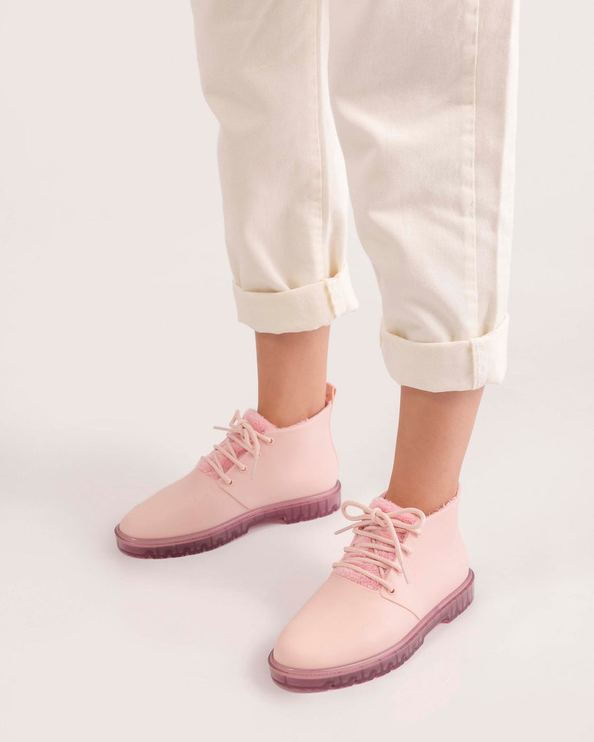 A model's legs wearing a pair of pink Melissa Fluffy Boots with laces and a rubber sole.
