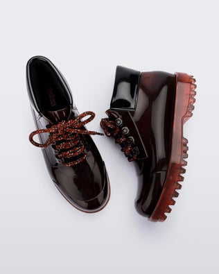A top and side view of a pair of brown / black Melissa Ares combat boots with a translucent brown/black base, brown patterned laces, black top back and translucent brown sole.