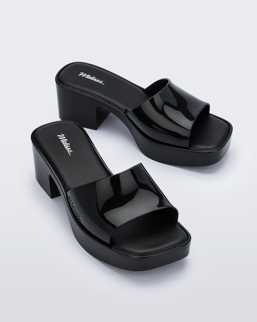 Angled view of a pair of Melissa Shape slides in black with a platform heel. 